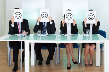 Row of business executives with smiley faces in front of their faces
