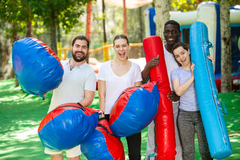 Portrait of happy friends with inflatable logs and pillows at an amusement park